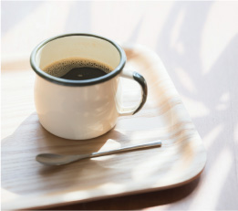 窓から光を浴びたマグカップに入ったコーヒー