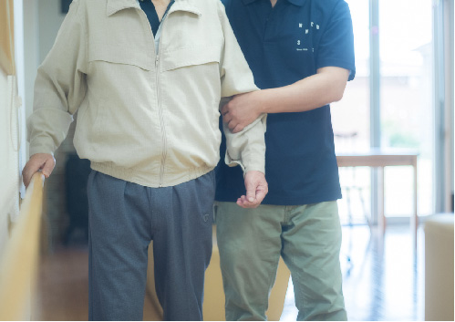 スタッフの補助を受けながら歩行訓練をする万倍の里利用者